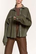 Load image into Gallery viewer, Model wearing an olive green ribbed button-front shacket with contrast panels and two chest flap pockets.
